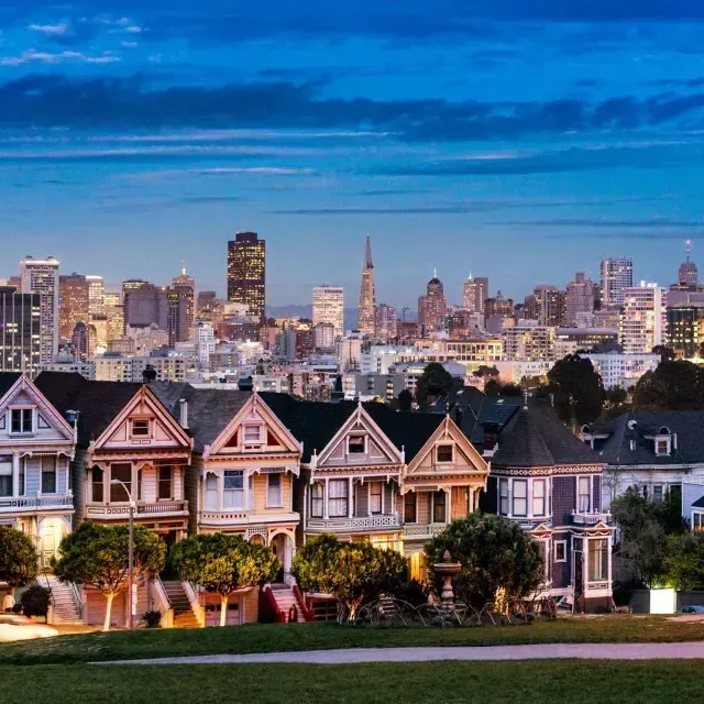 Le famose Painted女士 di Alamo Square sono raffigurate davanti allo skyline di 贝博体彩app al crepuscolo.